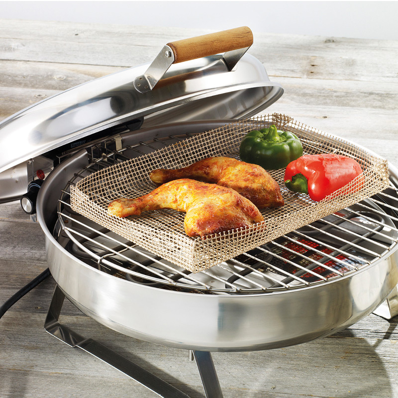 Avoin sähkögrilli puupöydällä, kanareisipalat ja punainen sekä vihreä paprika verkkoritiläkorissa.