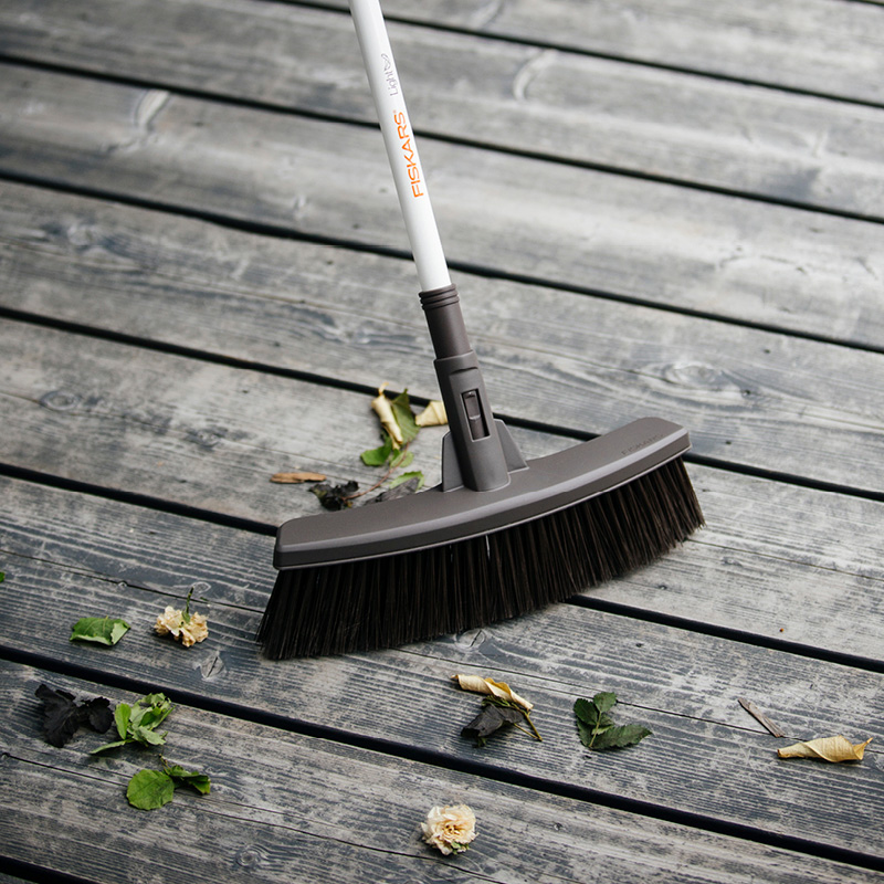 Harmaalla terassilla Fiskars-harja pyyhkii vihreitä ja ruskeita lehtiä