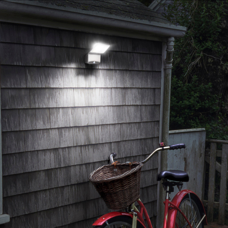 Harmaaseinäisen piharakennuksen kirkas LED-valo ja etukorillinen punainen polkupyörä.