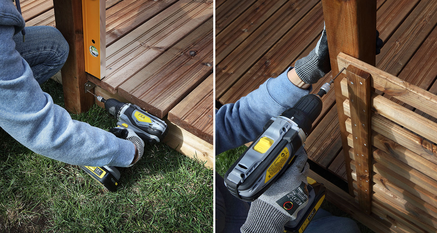 Ulkonurkassa kelta-harmaa 18 V porakone kiinnittää metallikulman ja puulistan ruskeaan terassiin