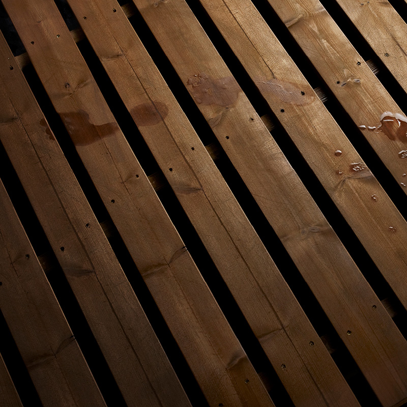 Vinot ruskeat puulankut mustilla raoilla ja kosteilla läikillä.
