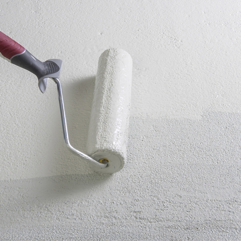 Kuvassa levitetään seinälle valkoista pohjamaalia telalla.
