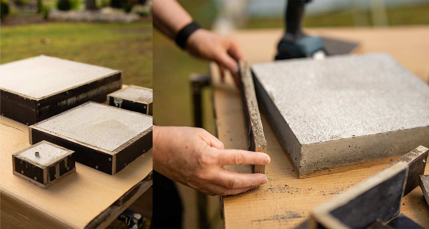 Puutarhapöydällä harmaita betonilaattoja mustissa puumuoteissa, kädet irrottavat muottia