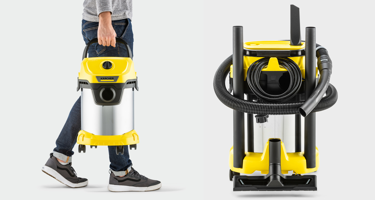 Henkilö kantaa keltaista Karcher-märkäkuivaimuria; taustalla imurin takasivu, letku ja tarvikkeet.