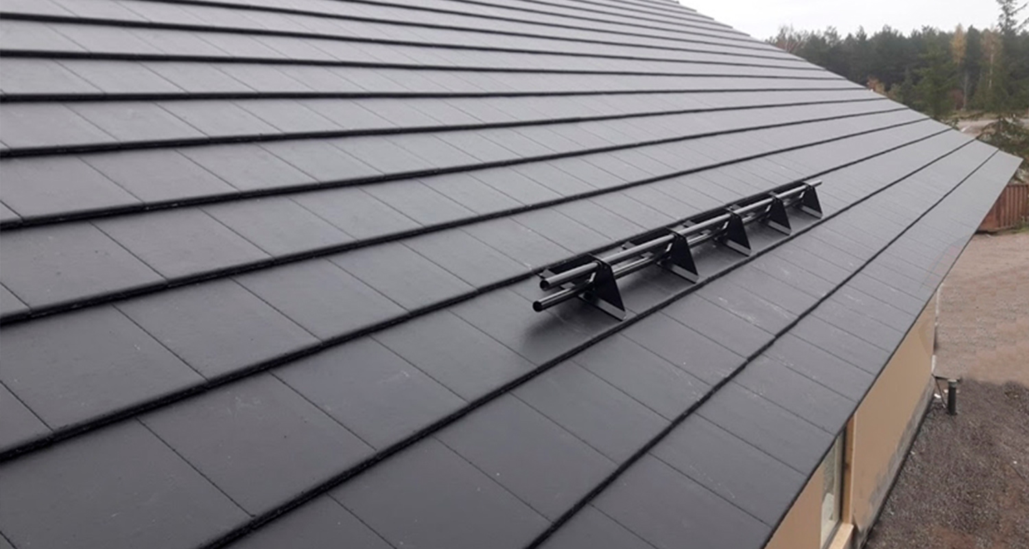 Musta harjakatto, keskellä musta putkilumieste, taustalla havumetsää.