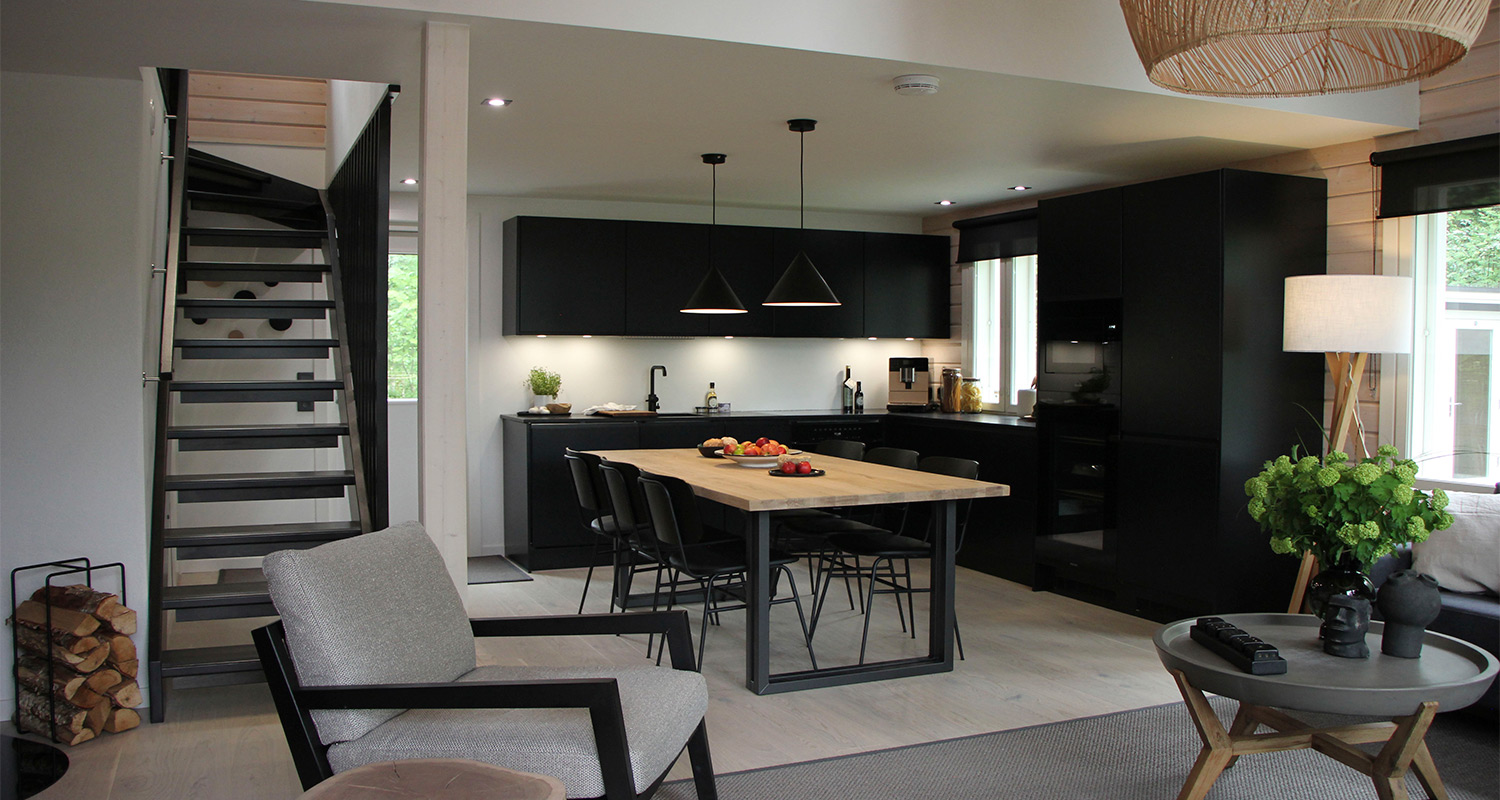 Huvila & Huussi ja K-Rauta remontoivat Bull Mentulan kesämökin. Kuvassa mökin remontoitu olohuone, keittiö sekä upeat mustat keittiökalusteet ja olohuoneen kalusteet.