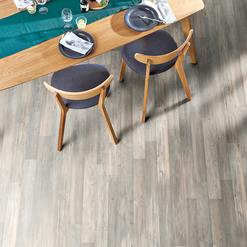 Yläkuva puupöydästä sinivihreällä kaitaliinalla, kahdesta harmaasta tuolista ja kattauksesta