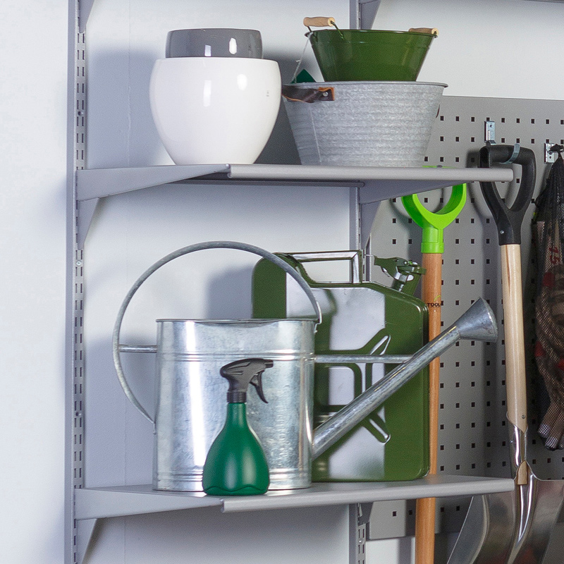 Harmaat ja vihreät puutarhatarvikkeet hyllyllä: kastelukannu, jerrykannu, suihkepullo ja lapioita