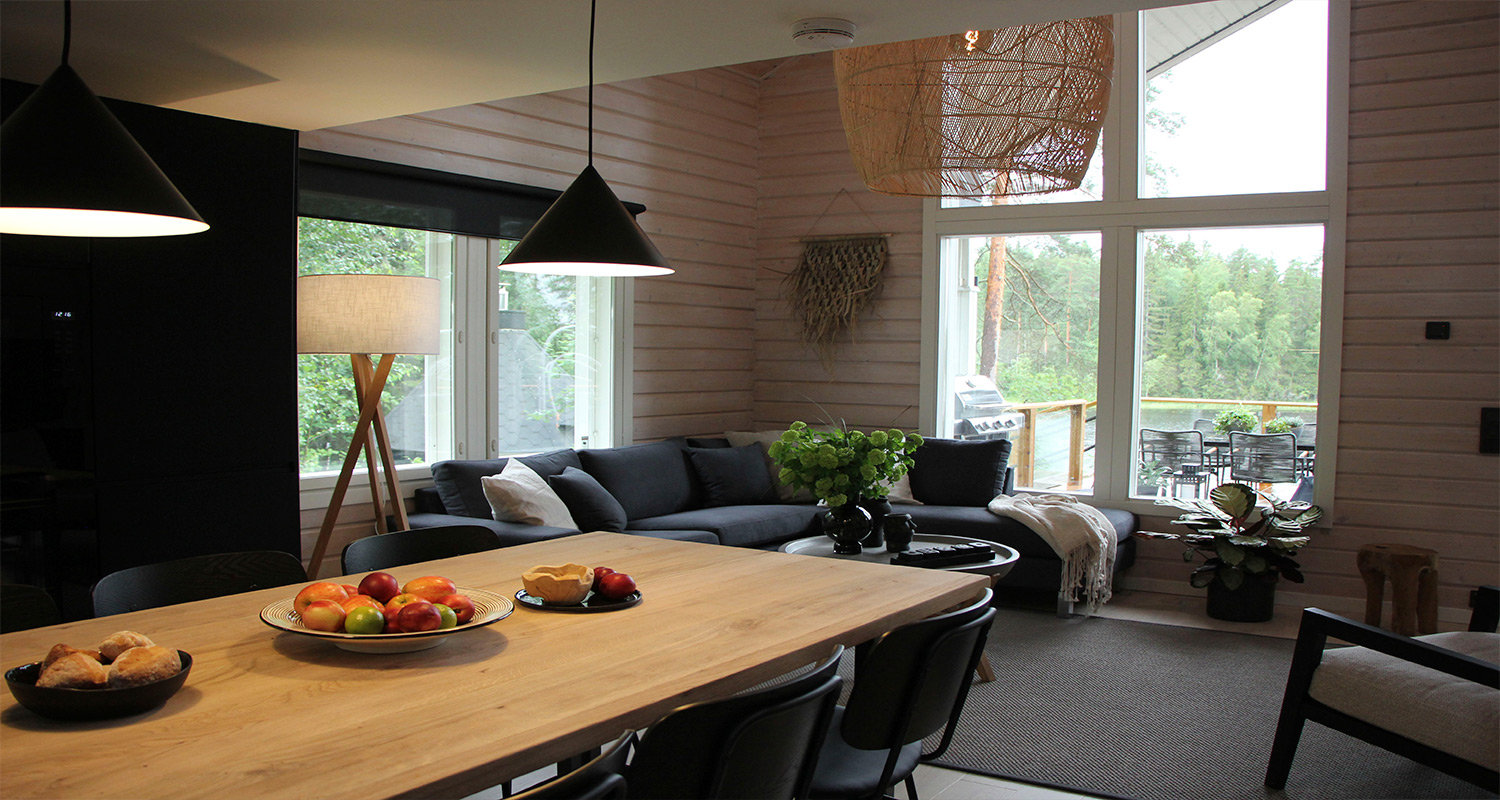 Huvila & Huussi ja K-Rauta remontoivat Bull Mentulan kesämökin. Kuvassa mökin remontoitu olohuone, keittiö sekä upeat mustat keittiökalusteet ja olohuoneen kalusteet.