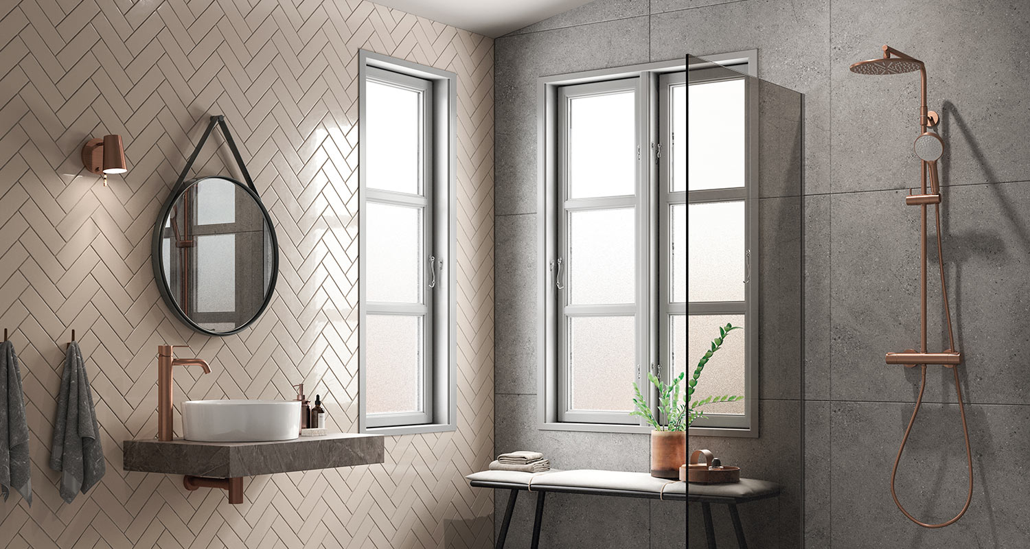 Kylpyhuone, jossa vaaleanpunertavaa kalanruodon malliin ladottua seinälaattaa ja suurta harmaata laattaa. Kuvassa näkyy myös Damixan hana ja suihku.