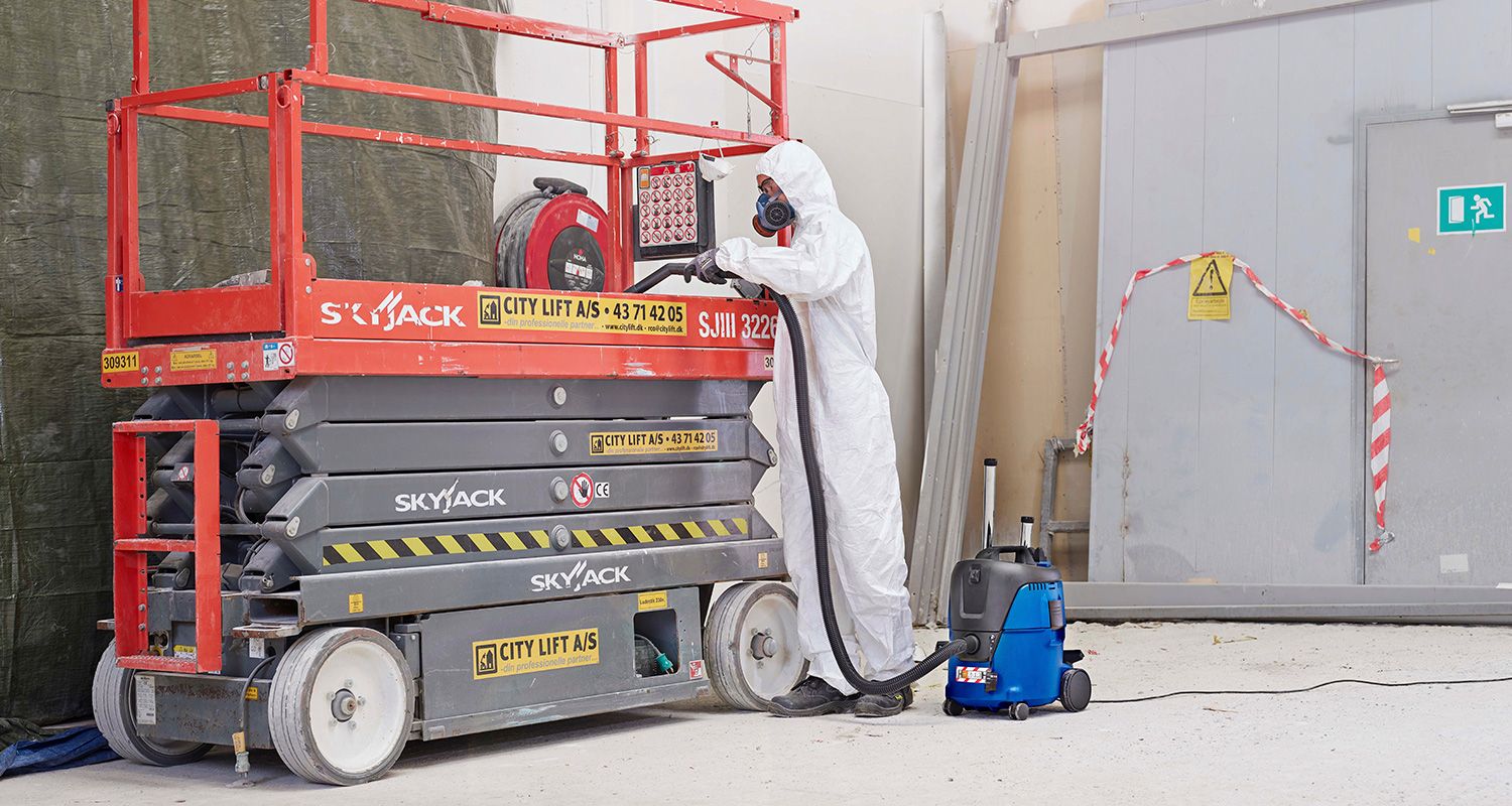 Työmies suojapuvussa ja märkä-kuivaimuri Nilfisk Aero 21-0H PC