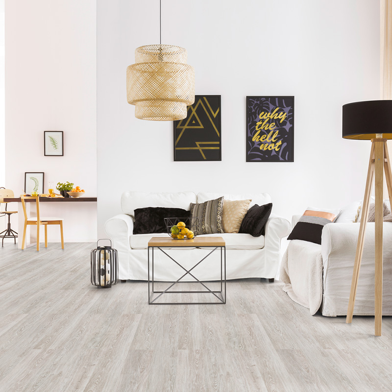 Vaalea skandinaavinen olohuone: valkoinen sohva, musta-keltaiset taulut, rottinkivalaisin