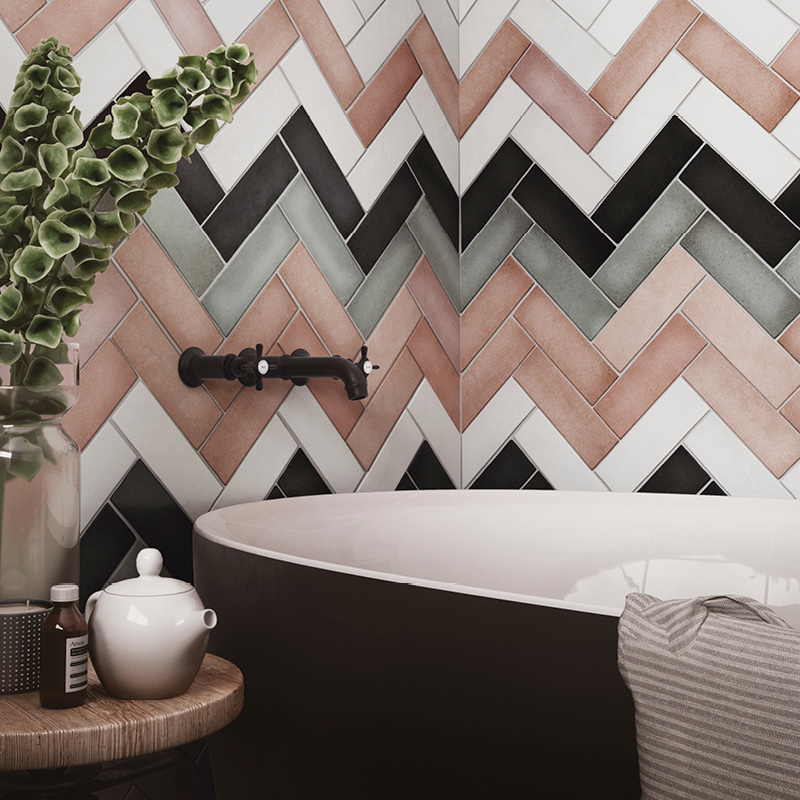 Musta-valkoinen kylpyamme kalanruotolaatoitetun terrakotta-, vihreä- ja mustaseinän edessä.