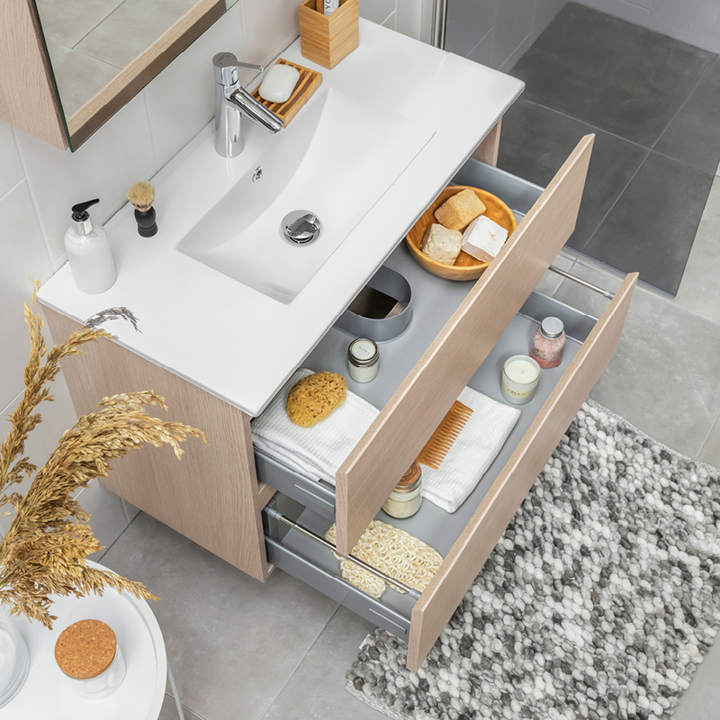 Valkoinen allas vaaleassa puukaapissa, avoimet laatikot pyyhkeitä ja pesuvälineitä