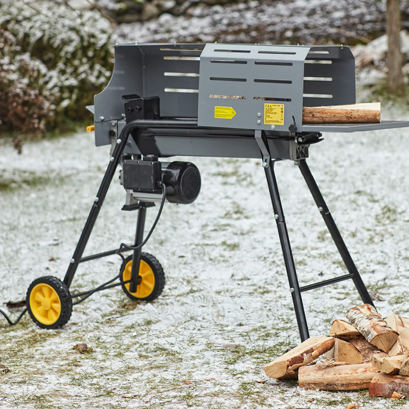 Harmaa ja musta polttopuiden halkomakone keltaisilla pyörillä lumisella nurmella