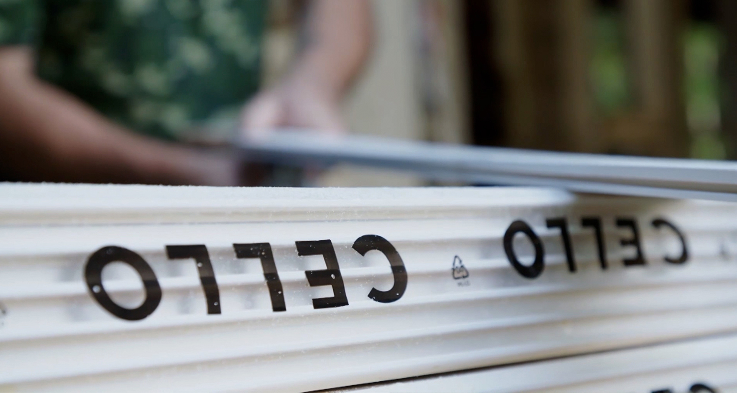 Pino valkoisia uritettuja muovilevyjä mustalla CELLO-logolla rakennustyömaalla