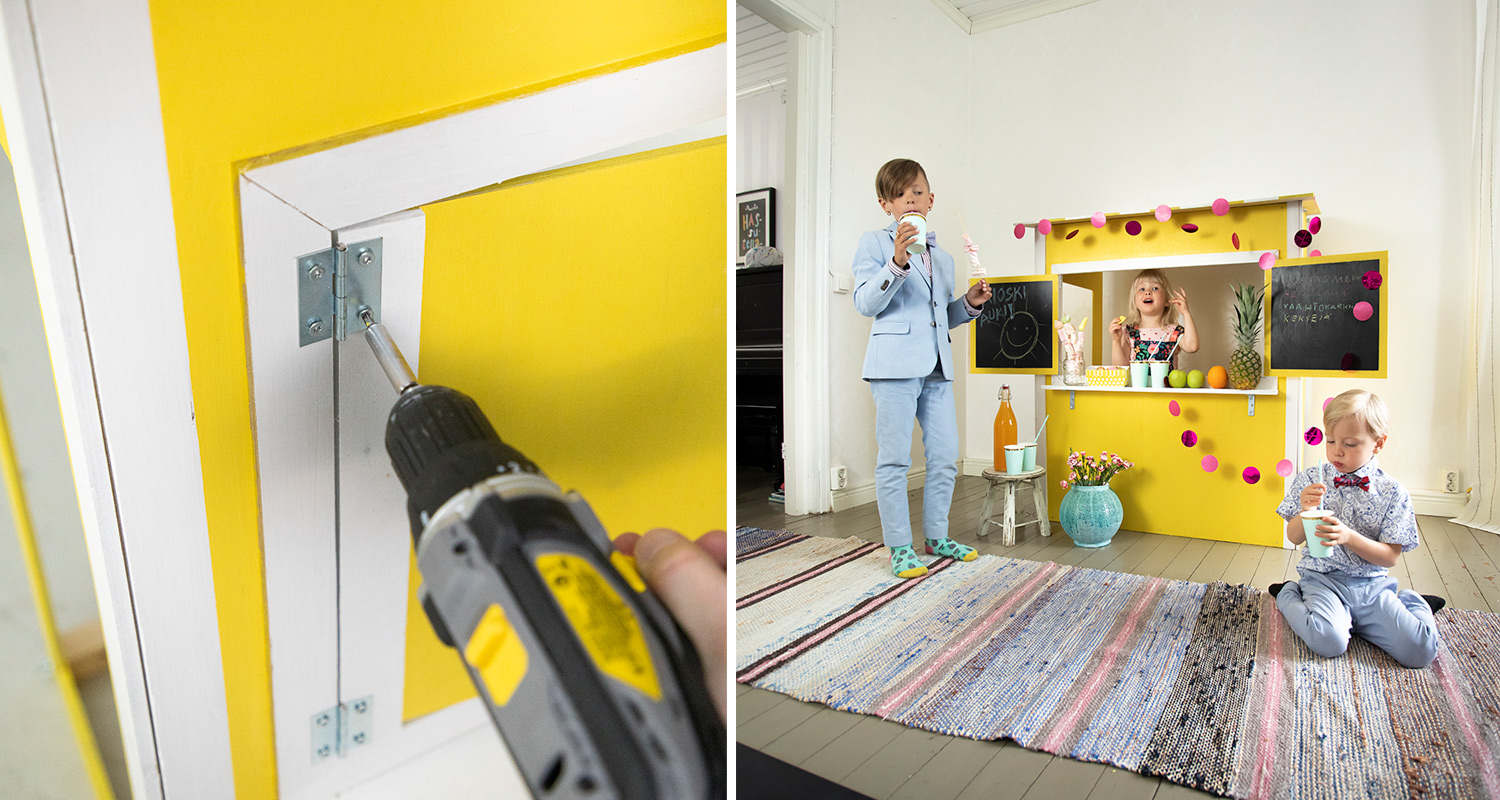 Sisätilan keltainen mehukoju pinkein koristein ja liitutauluin, lapset juovat mehua.