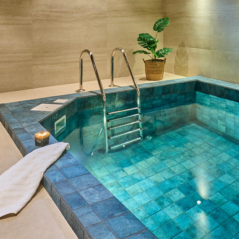 Helsinkiläisen taloyhtiön kylpylätunnelmaa henkivällä uima-allasosastolla kelpaa rentoutua. Kuvan laatat tilausvalikoimista.