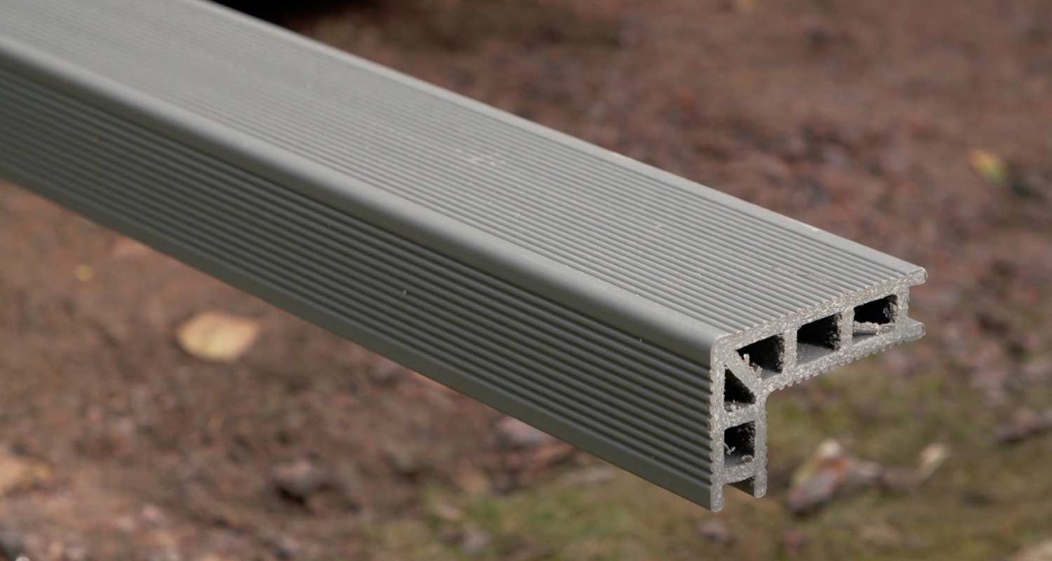 Harmaa, uritettu komposiittipalkki ulkona, avoin pää paljastaa ontelot.