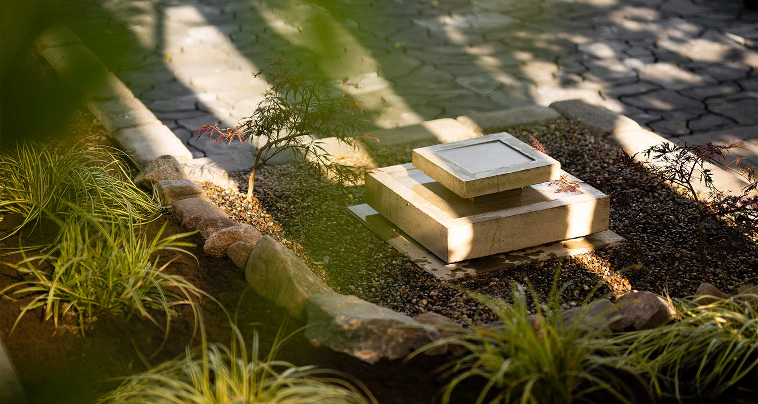 Betoninen kolmikerroksinen vesiaihe kivipäällysteisessä zen-puutarhassa, varjot.