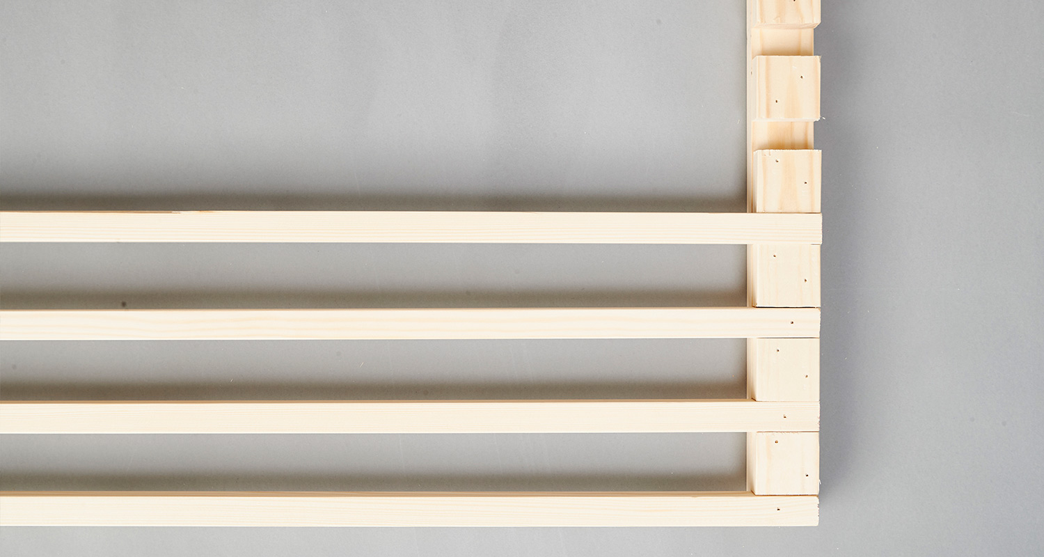 Vaaleat puulistat neljässä vaakarivissä harmaata pintaa vasten.