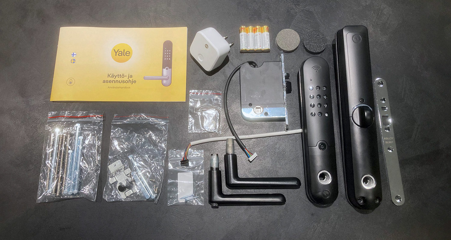 Kuvassa avatut pakkaukset Älylukko Yale Doorman L3 musta ja wifi-silta Yale Connect Wi-Fi Bridge, tuotteet K-Raudasta 
