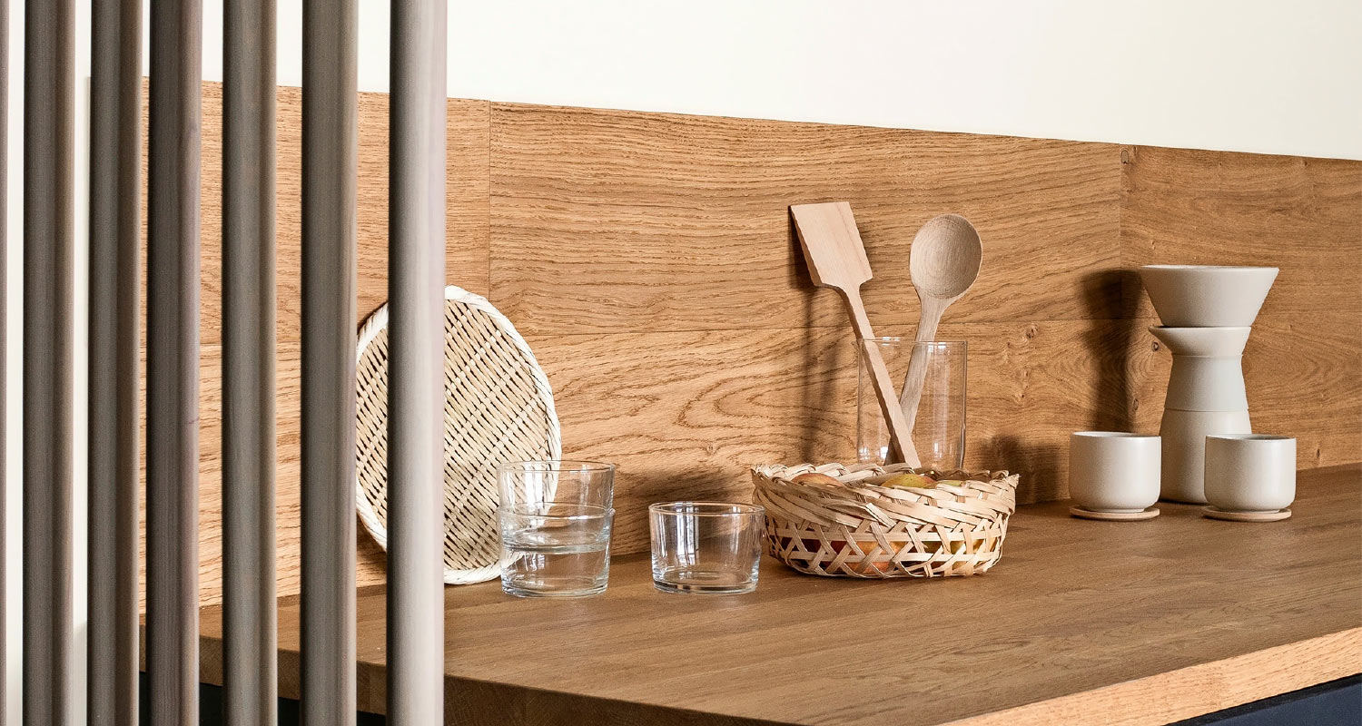 Vaaleapuinen keittiötaso, lasi- ja keramiikka-astiat, rottinkikori ja puuvälineet