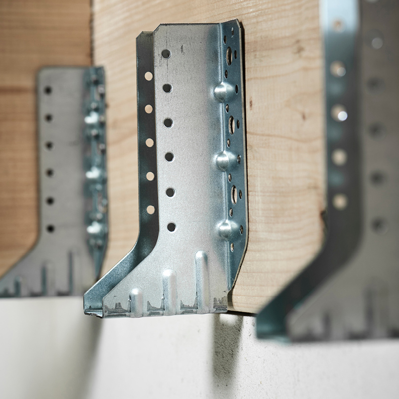 Alt: Galvanoituja teräskulmaliittimiä puupalkin reunassa vaaleassa rakennustilassa.