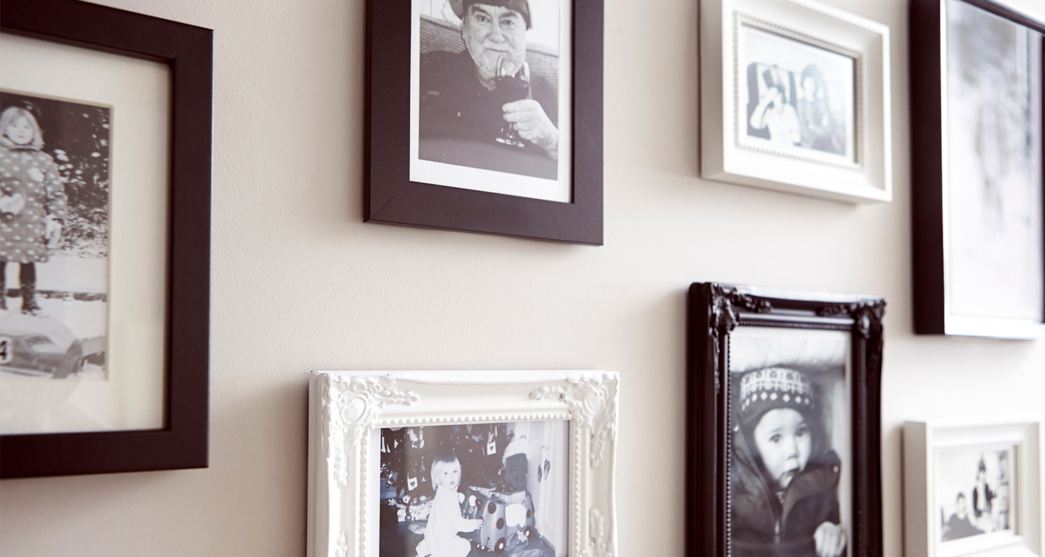 Beige seinä, jossa rivi mustia ja valkoisia koristeellisia valokuvakehyksiä.