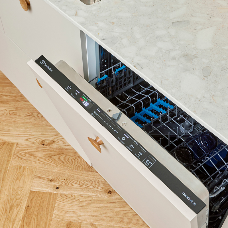 Avoinna oleva Electrolux-astianpesukone valkoisessa keittiössä, harmaa kivitaso ja puulattia.