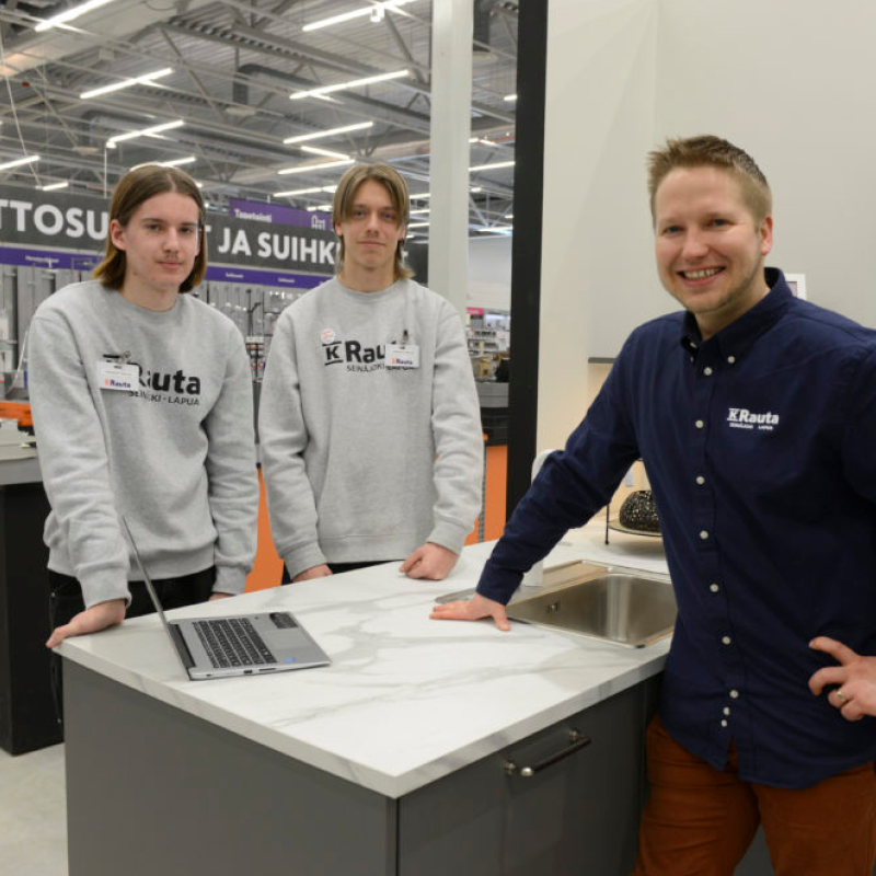 Kolme K-Rauta-työntekijää esittelee marmoroitua keittiötasoa ja allasta.