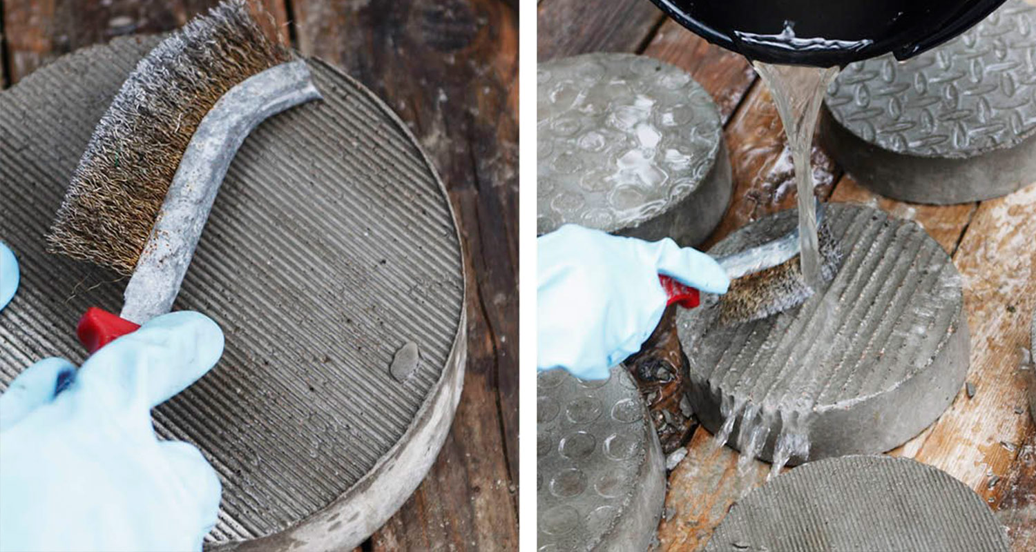 Sinikäsineinen käsi harjaa pyöreää uritettua metallilevyä ja huuhtelee sitä vedellä.