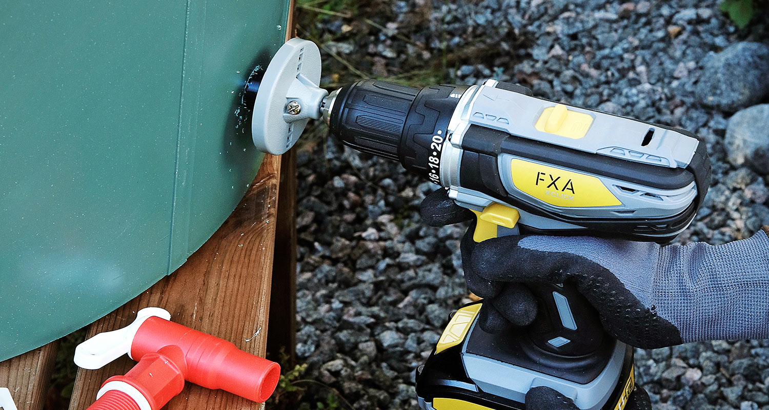 Mies rakentaa sadevesitynnyrin näkösuojaa. Kuvassa kiinnitetään sadevesitynnyriä.