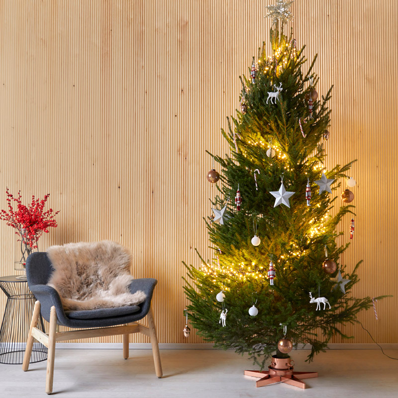 Kuvassa joulukuusi puisessa sisustuksessa. Joulukuusessa valot ja koristeet.