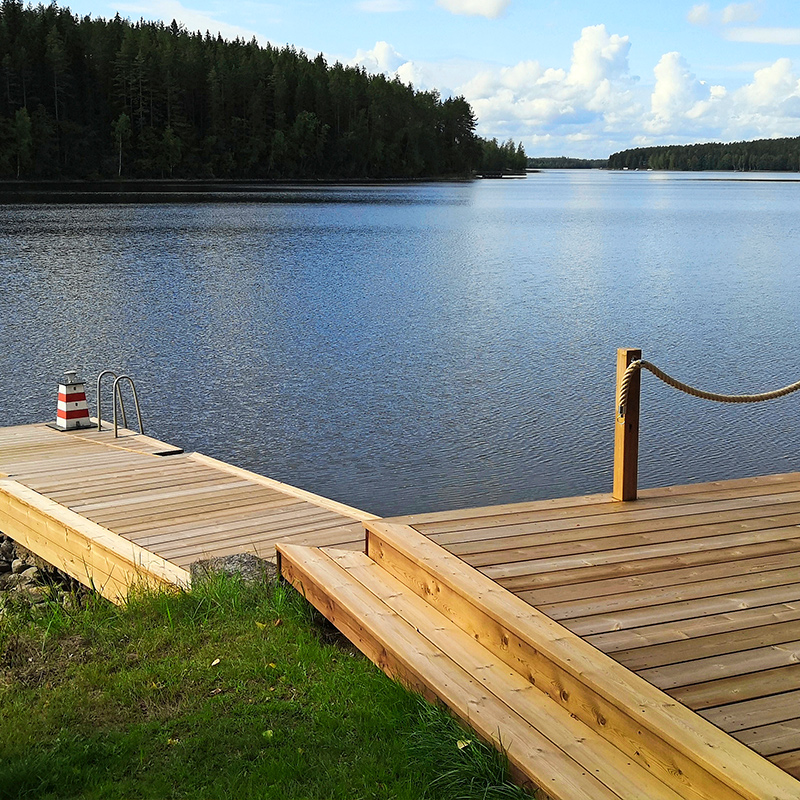 Vaalea puulaituri järven rannalla sininen vesi tumma metsä ja pilvinen taivas