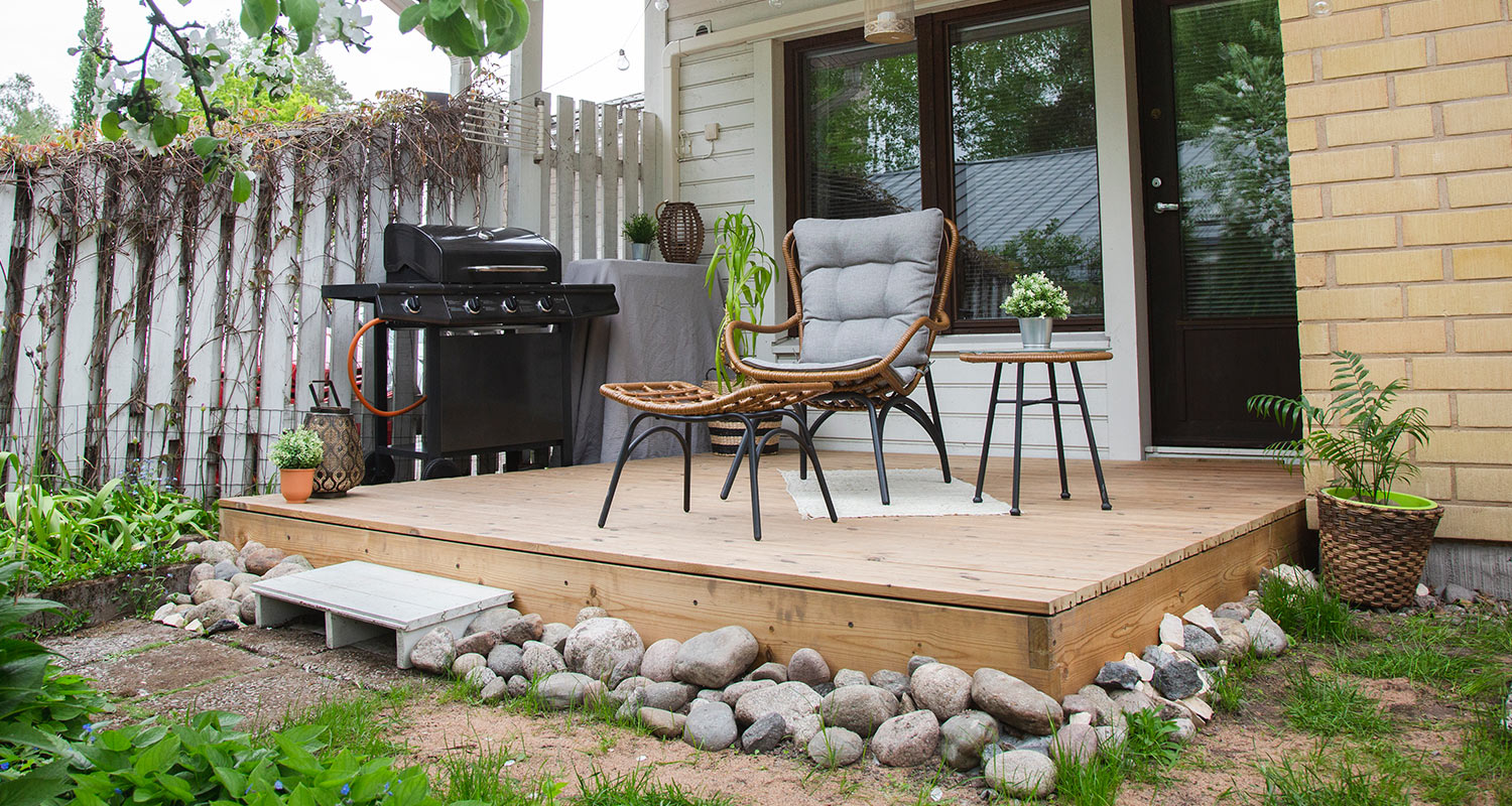 Cellon valmisterassi pienellä pihalla mustan grillin kera 