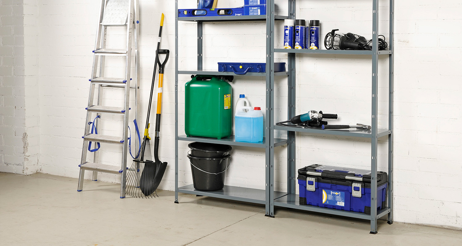Metallihylly valkoisella seinällä, tikkaat, lapio, vihreä kanisteri ja sinimusta työkalupakki