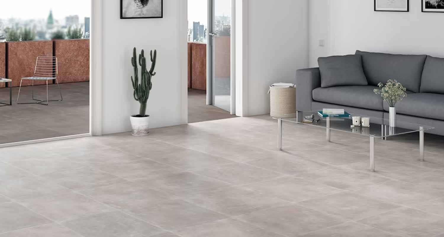 Vaalea olohuone harmailla laatoilla, harmaa sohva, lasipöytä, kaktus ja parveke kaupunkinäkymällä