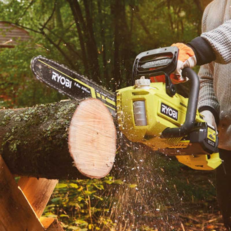 Henkilö sahaamassa keltaisella Ryobi-ketjusahalla pölliä metsässä, puunlastuja leijailee.