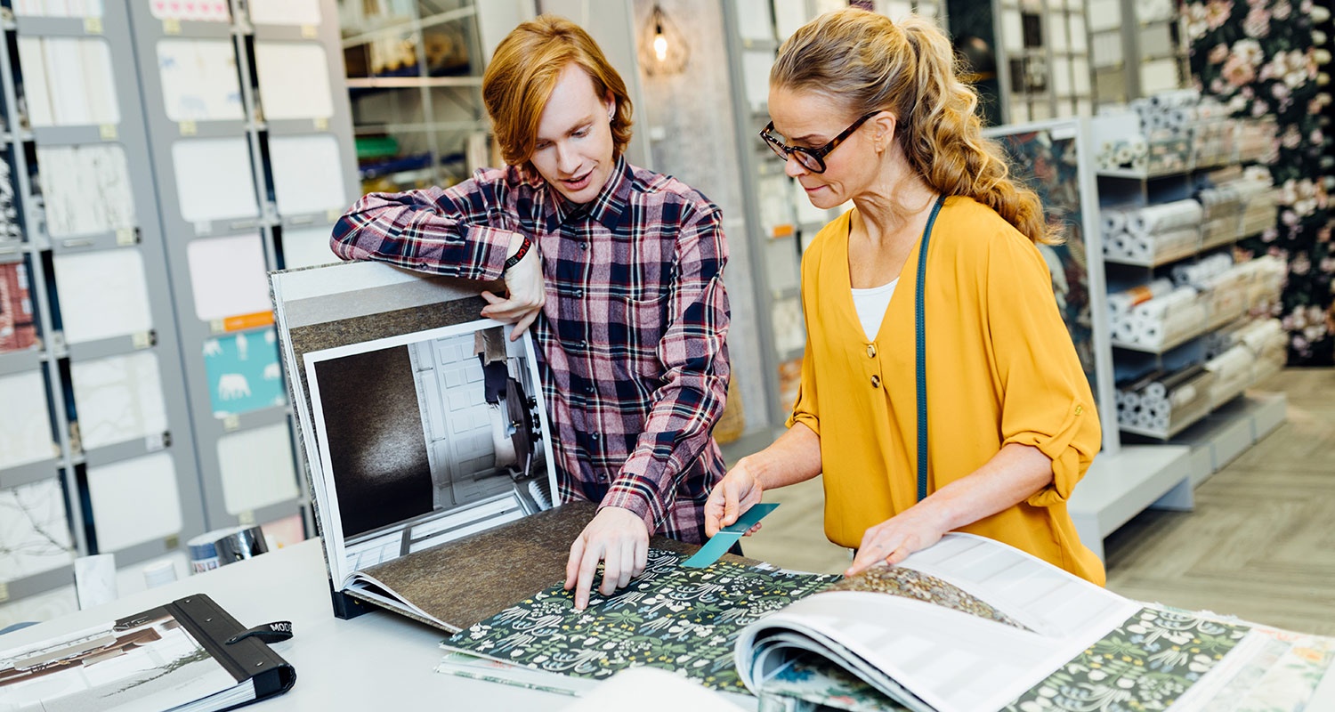 Poika ja nainen tutustuvat tapettivaihtoehtoihin K-Raudassa