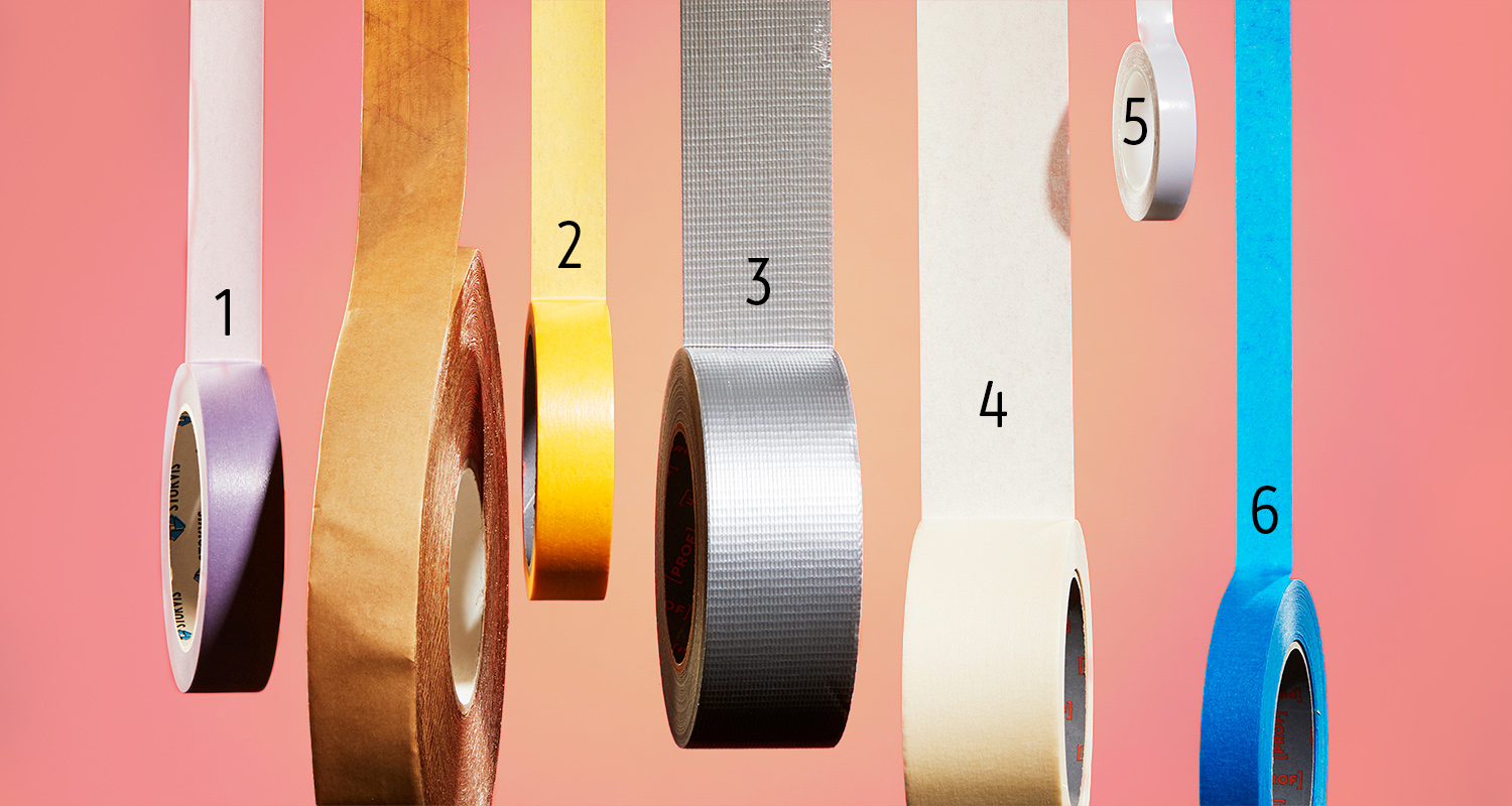 Kuusi teippirullaa roikkuu eri kirkkain värein vaaleanpunaisella taustalla