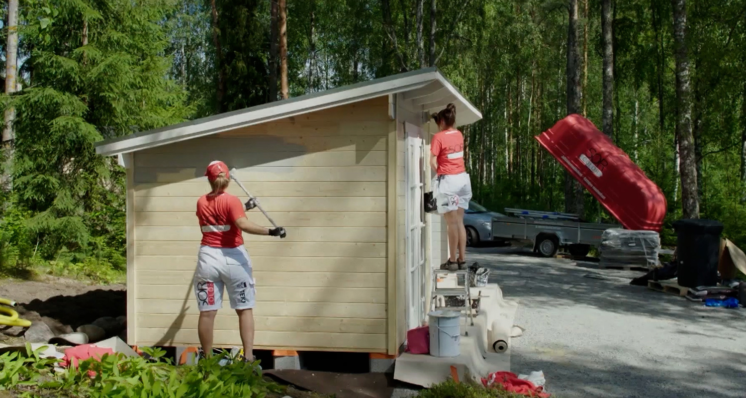 Punapaitaiset maalarinaiset maalaavat vaaleaa puuvajaa metsäaukiolla.