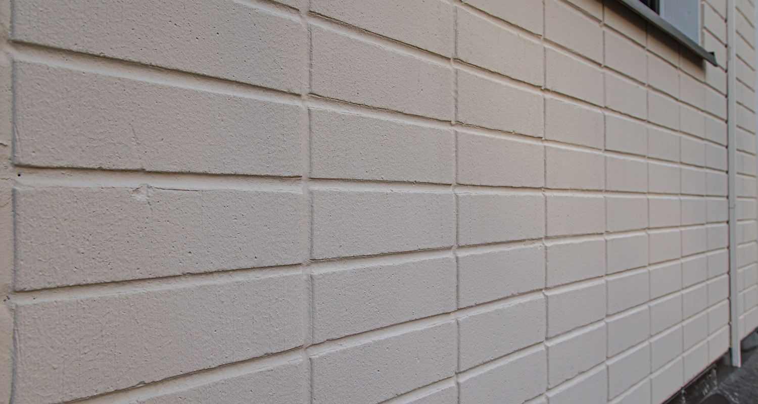 Lähikuvassa Tikkurilan Kivitex Brick House Paint -tiilitalomaalilla maalattu tiilijulkisivu.