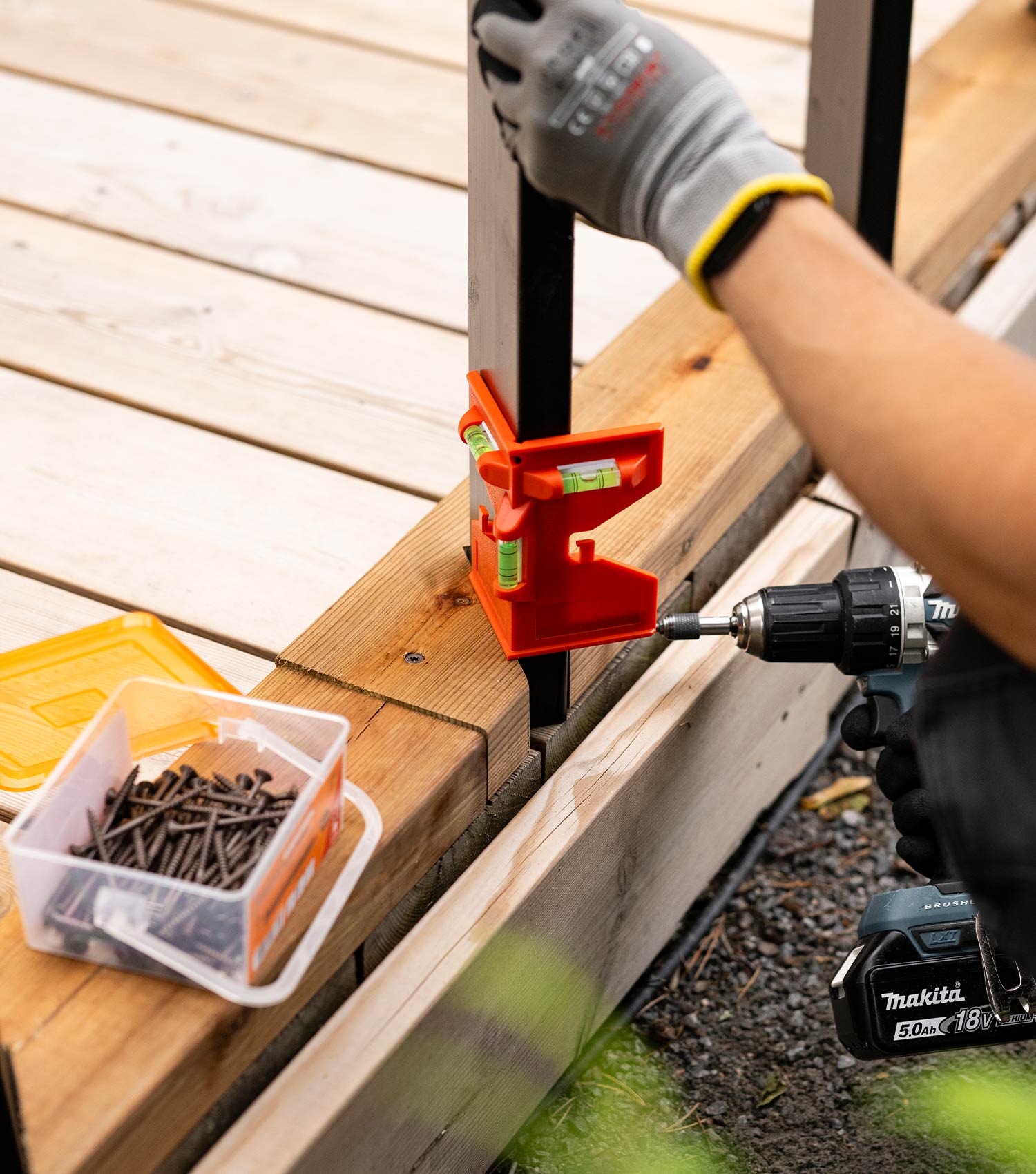 Tee itse terassikaide: Mies asettaa maalatut pystypuut alarunkopuuhun