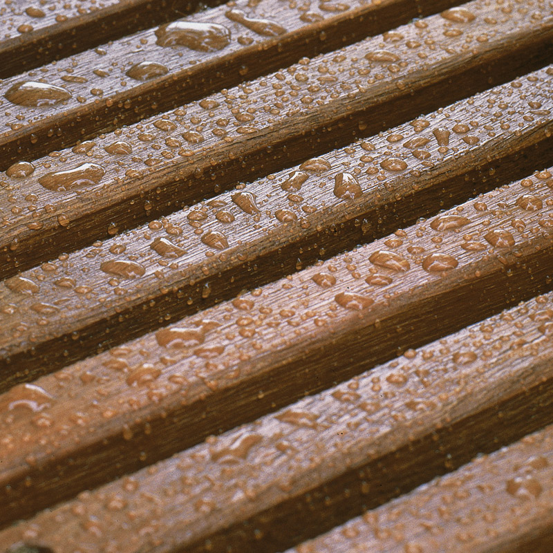 Vaakasuorat ruskeat puulaudat sadepisaroiden peitossa.