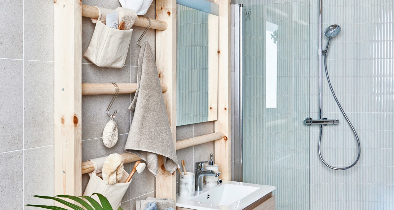 Vaalea kylpyhuone, puinen tikkahylly beige pyyheellä ja toilettipussilla, pesuallas ja lasinen suihku