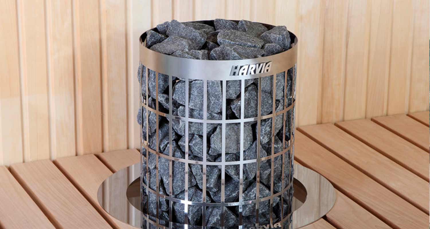 Harvian ruostumaton teräskiuas täynnä mustia kiviä vaaleassa puusaunassa