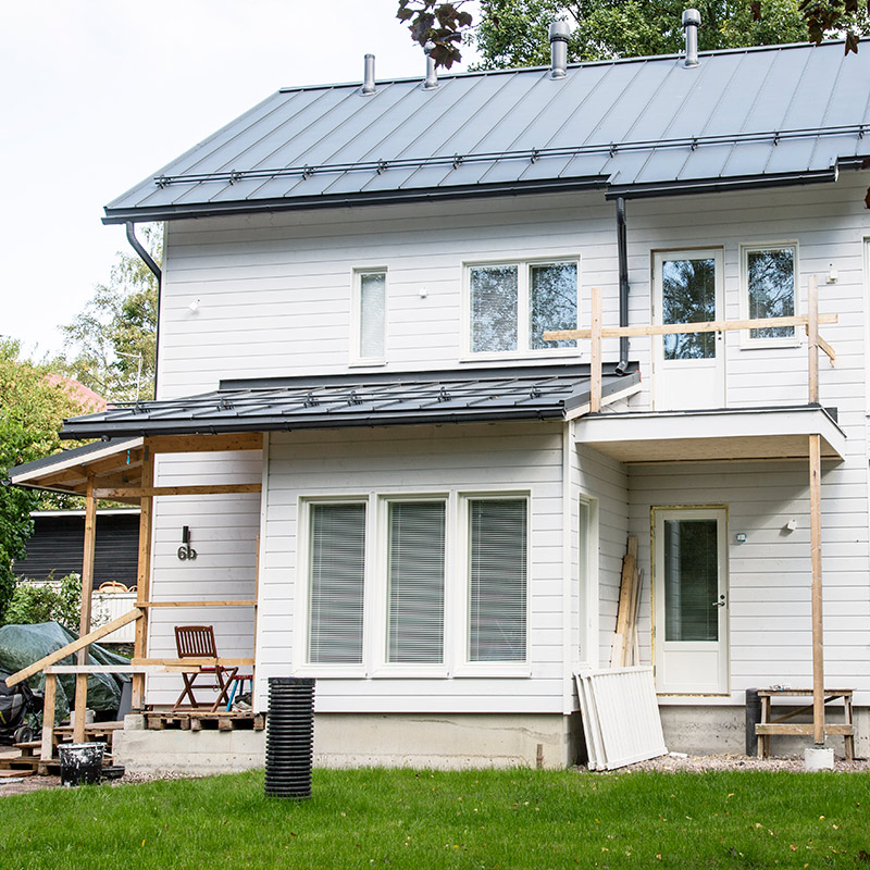 Valoinen suuri puuomakotitalo, julkisivun maalaus menossa