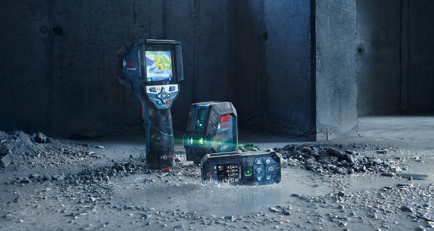 Bosch-lämpökamera, laserlinjain ja mittalaite märällä betonilattialla rähjäisessä työmaassa