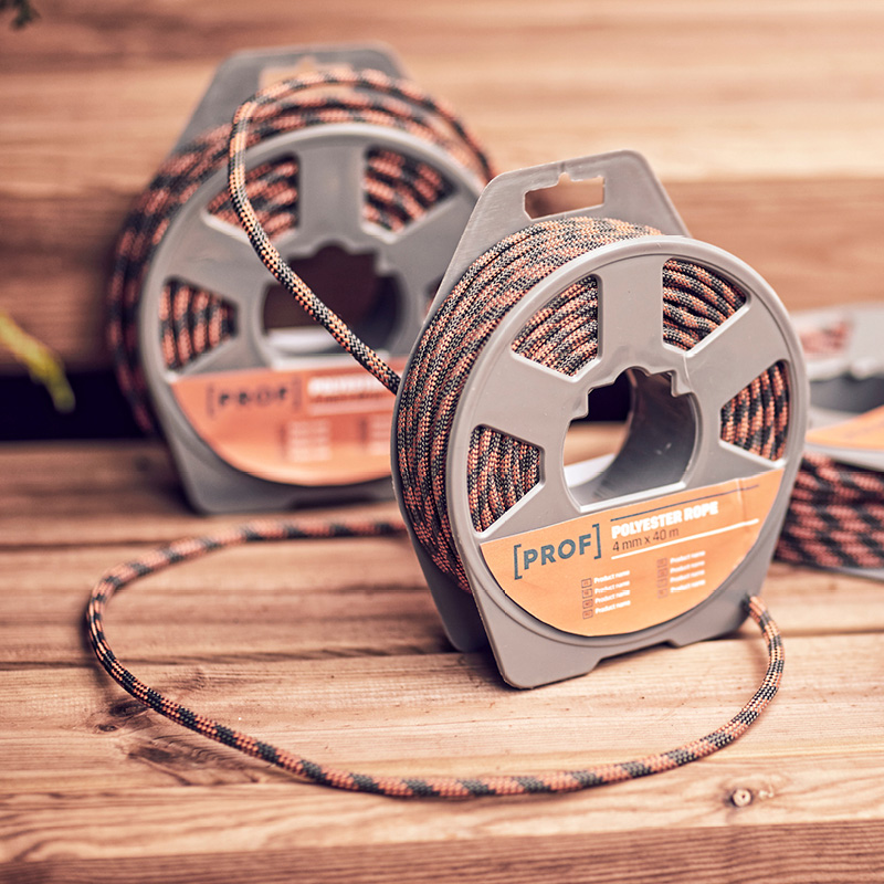 Kaksi muovirullassa olevaa oranssi-musta-vihreää polyesterinarua puisella pöydällä